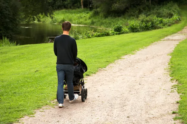 Man som går med barnvagn i en park. Mostphotos.