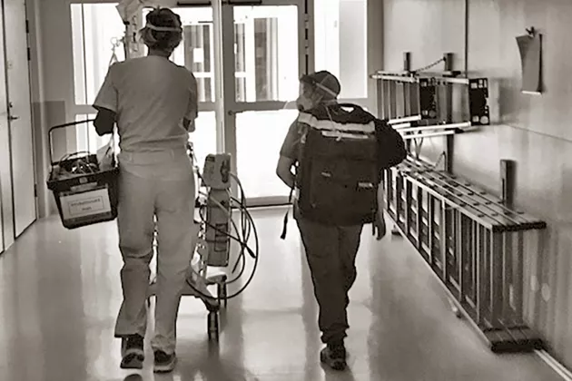 Två sjukvårdsanställda går i en korridor. Foto. 