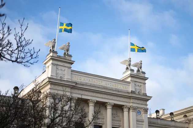 Bild på universitetshuset med flaggor på halv stång.