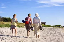 tre kvinnor som promenerar på stranden.